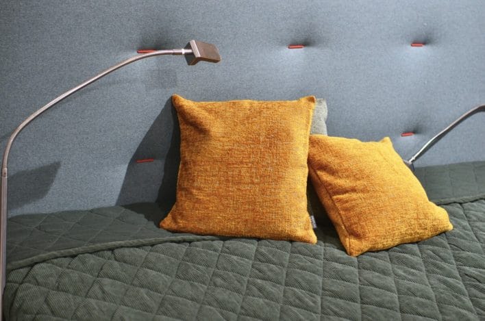 Bright orange cushions on soft bed under lamp