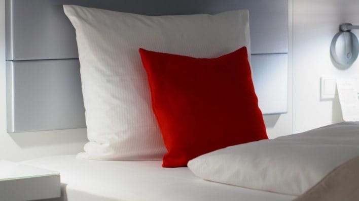 the headboard of a bed with a white and red pillows 
